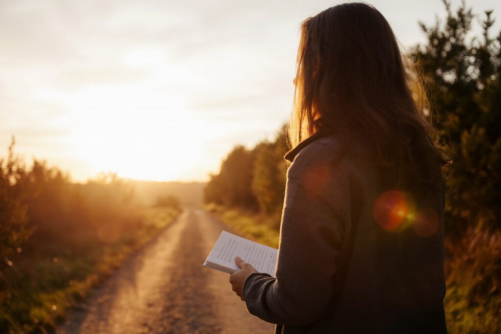 Person walking at sunset with journal, symbolizing progress